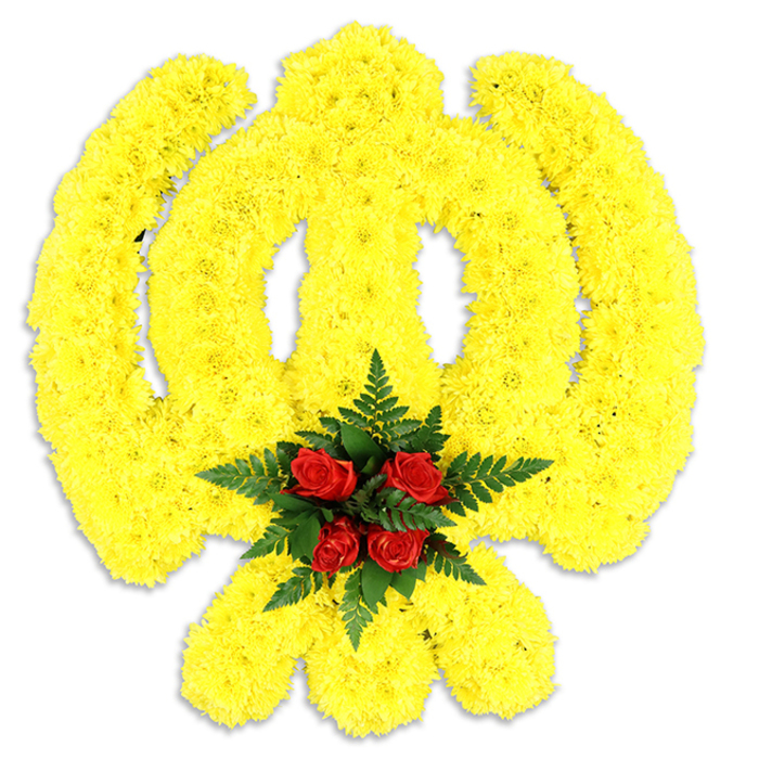 A large, emblematic Khanda fashioned entirely from bright yellow chrysanthemum blooms fills the frame, its religious components - the outer chakkar, the central double-edged khanda and the paired kirpans - precisely traced in a dense mosaic of tiny petals. The chrysanthemums are packed so closely that the surface reads plush and slightly rounded, a soft architectural texture that gives the symbol presence and a quiet luminosity against the stark white background. At the very centre, where the elements converge, a concentrated cluster of deep red roses commands attention: five to six buds set tightly together and cushioned by dark green fern fronds whose linear blades add contrast and a calming, matte depth. The yellows are optimistic yet respectful; the crimson core reads as a point of focused remembrance. A delicate grey shadow beneath the piece indicates its physicality-likely a stand-alone wreath or tabletop tribute-ready to be placed at a memorial, funeral service or cultural event. The overall scent profile would be understated: chrysanthemum's gentle sweetness, rose's familiar richness, and the fern's cool, green counterpoint. As a florist who knows Greenhithe streets and community rhythms, I picture this arranged for a gurdwara service or civic remembrance at locations familiar to residents-near the riverbank, by Ingress Park, or for gatherings that draw neighbours from Swanscombe and Castle Hill. The workmanship is traditional and respectful, designed to communicate honour and continuity through colour, texture and symbolic fidelity, making the piece a meaningful option for those seeking to mark Sikh heritage with dignity.