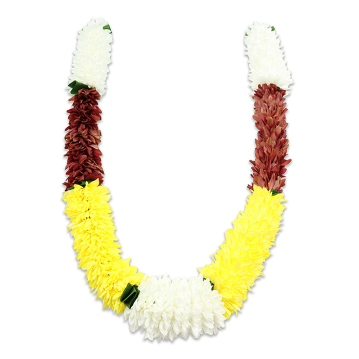 A vividly segmented, U-shaped floral garland sits against a pure white backdrop, its form and colours described with the precision of a local florist who knows the neighbourhoods of Greenhithe and nearby Ebbsfleet. Beginning at each top tip is a compact cylinder of creamy white blooms - small, cushiony petals that recall jasmine or miniature chrysanthemums - leading into a substantial band of deep maroon, a warm reddish-brown that provides a solemn contrast. The dominant lower curve is made of a long run of bright yellow flowers, densely arranged to produce a full, cheerful sweep that visually lifts the design. Where the two yellow arms meet at the bottom, a broad cluster of stark white, chrysanthemum-like blooms becomes the visual centrepiece, tastefully punctuated by little dark green leaf accents that break the colour fields and evoke a hint of natural foliage. Close inspection reveals thousands of fabric petals, each carefully layered and stitched to achieve a consistent, plush surface built for ceremonial use. This type of mala is traditionally used in Hindu pooja, temple offerings, weddings or festivals such as Diwali and Holi, and the colour trio - white, yellow and maroon - speaks to purity, prosperity and devotion. As a Greenhithe florist I see customers choosing similar garlands for family rites or community events near the riverfront, by the Bluewater roundabout and along Station Road. Flower Delivery Greenhithe crafts and sources pieces like this for local ceremonial needs, balancing traditional form with durable materials suited to repeated handling.