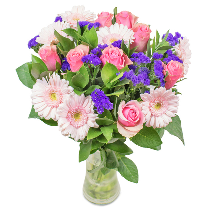 A striking, professionally composed bouquet from Greenhithe stands tall in a clear glass vase, set before an immaculate white backdrop. Central to the arrangement are around seven to nine medium pink roses, their petals spiraling tightly or just beginning to reveal graceful hearts, providing a sense of romance and soft tradition. Five to seven pale pink gerbera daisies encircle the roses, their large, sunny faces and layered petals exuding energy and warmth. Vivid purple clusters of statice nestle between the larger blooms, adding a subtle complexity and a deeper thread of colour-an inspired choice by local florists. Abundant, lush green foliage both anchors and uplifts the bouquet, evoking Greenhithe's connection to nature and the gentle flow of the Thames nearby. The vase's transparency highlights the freshness of every stem and the pristine water, reinforcing the arrangement's suitability as a fresh flower delivery or a cherished gift for birthdays, anniversaries, Mother's Day, or simply to brighten an office off Crossways Boulevard. This bouquet embodies joy, sophistication, and the skilled touch of Greenhithe's best flower artisans.